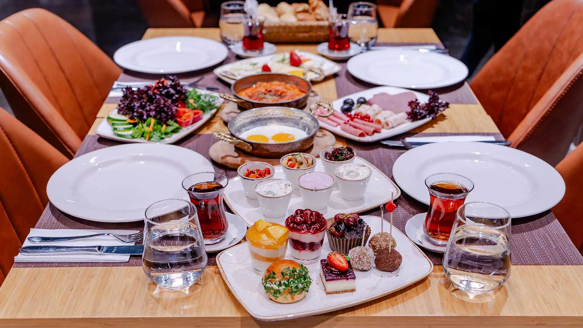 طاولة مليئة بمجموعة متنوعة من لذائذ الإفطار التركي وكوب من الشاي التركي الساخن.